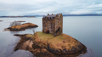 Castle Stalker stands majestically on a small island in Scotlands waters amid cloudy skies