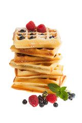Stack of Belgian waffles with blueberries, raspberries and confectioner's sugar isolated on white background