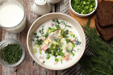 Delicious okroshka soup in bowl on wooden table, flat lay
