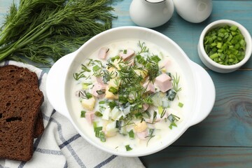 Delicious okroshka soup served on light blue wooden table, flat lay