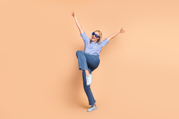 Young smiling businesswoman wearing casual blue shirt posing enthusiastically on beige background...