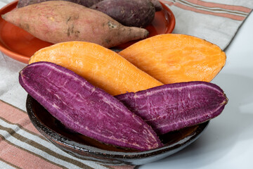 Colorful sweet-tasting tuberous roots vegetables purple and orange organic sweet potatos close up