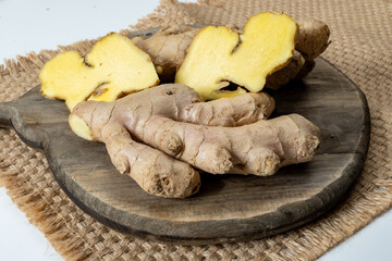 Fresh organic ginger rhizome root used in traditional medicines and for flavoring meals, drinks, on wooden board