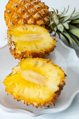 Two whole fresh ripe pineapples or sweet baby ananas on white background close up