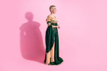 Fototapeta premium Elegant woman in Renaissance-style attire posing against pink backdrop highlighting classical fashion concepts