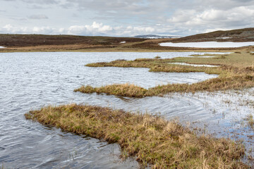 A small lake in the mountains with melting snow on the hill slope in mid June. Varangerhalvøya...