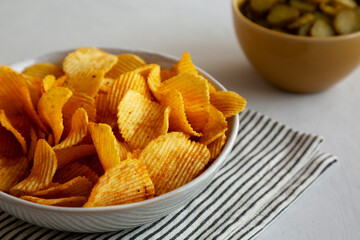 Crinkle Potato Chips and Green Pickle Chips in Bowls, side view.