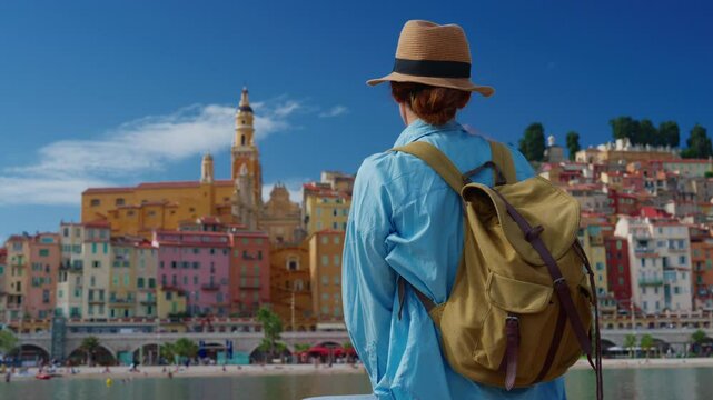 Colorful city on the French Riviera on the Mediterranean coast Menton. Girl in a hat sits and looks at the panorama of the colorful city of Menton