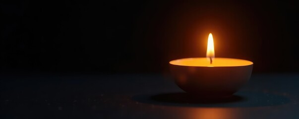 The soft glow of a candle flame on a black background creates a sense of calm, relaxation, peaceful