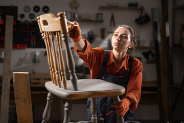 Diy woman painting and renewing old wooden chair at home workshop.
