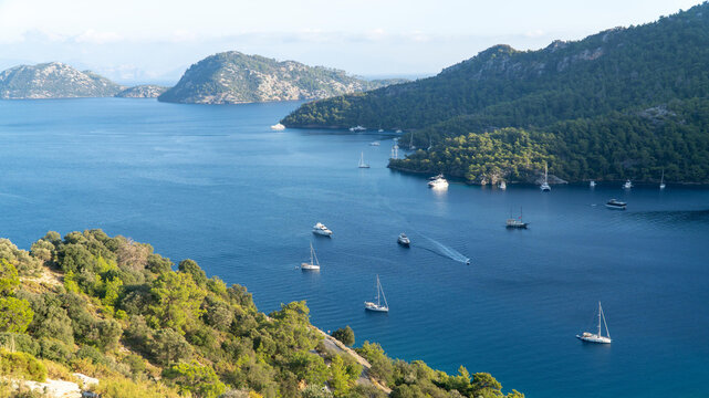 Sarsala Beach Bay in Dalaman, Turkey, a serene Mediterranean cove with crystal-clear waters, lush green hills, and anchored yachts, offering a perfect summer escape.