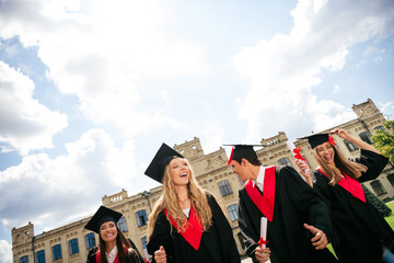 Group of young graduates celebrating achievement outdoors on a sunny day