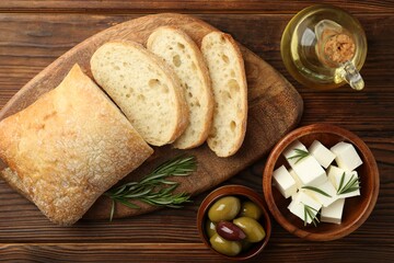 Delicious marinated olives, bread and feta cheese served on wooden table, flat lay