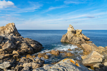 Massifs rocheux partiellement immergés dans une mer bleu profond sous un ciel légèrement voilé, sur la côte nord du Finistère en Bretagne. Un paysage authentique entre terre et océan.