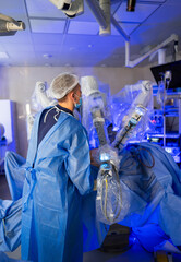 Robot surgery in progress. A medical professional operates a surgical robot in a sterile...