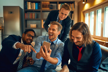 Young group of people using a smart phone while watching a sports game in the living room