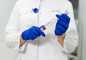 Pro prepares vaccine syringe. A healthcare worker holds a syringe filled with medication, ready for vaccination in a clinical setting.