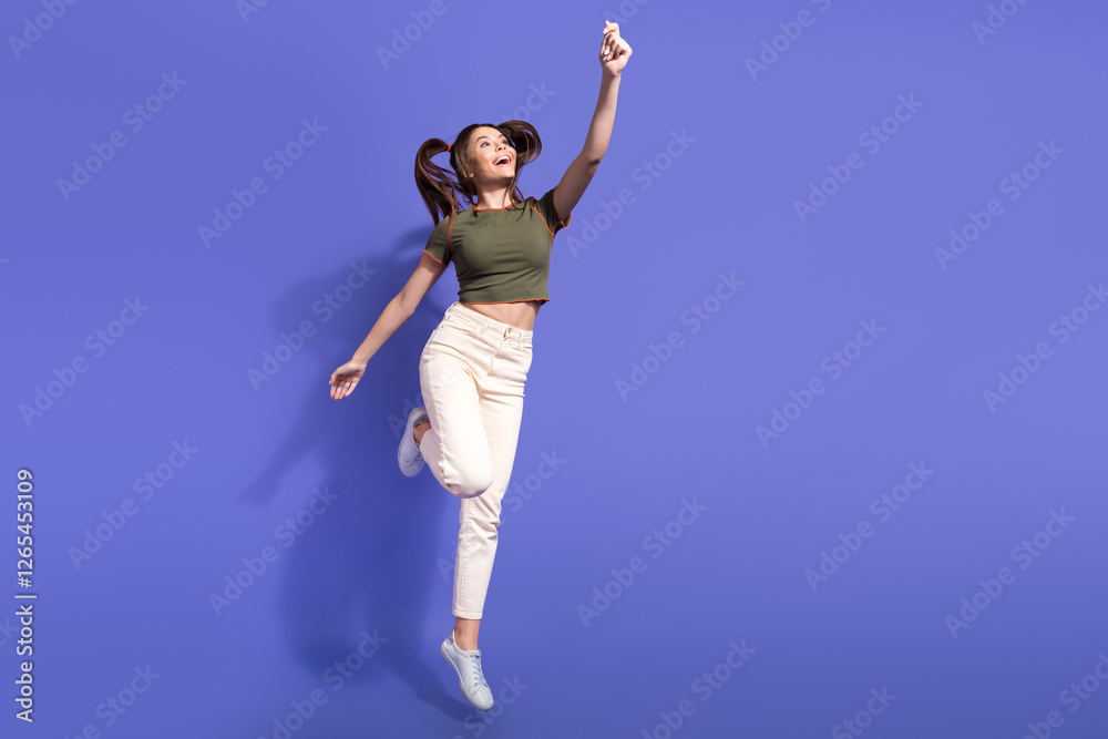 Wall mural Cheerful woman in casual outfit posing mid-air gesturing energetically on vivid violet background