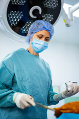 Surgeon in delicate operation. A medical professional in scrubs and mask focuses on a surgical...