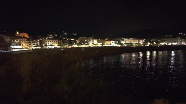 Night view of tossa de mar, a popular tourist destination on the costa brava, highlighting its illuminated beach and historic city walls