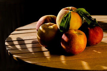 Ripe fresh juicy peaches in the shade on a wooden table