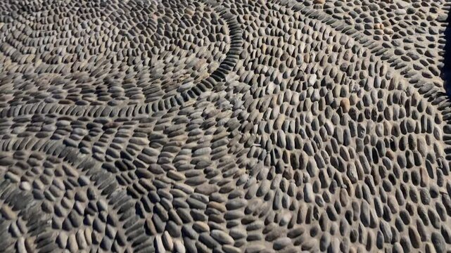 Footpath paved with pebbles and small cobblestones with night lighting