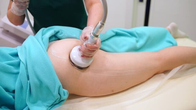 Professional masseuse using modern device for RF lifting procedure, health care and beauty treatments. Anti-cellulite massage in SPA salon, massaging back hips of woman.