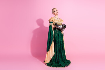 Fototapeta premium Elegant woman in historic attire and steel gloves on pink backdrop