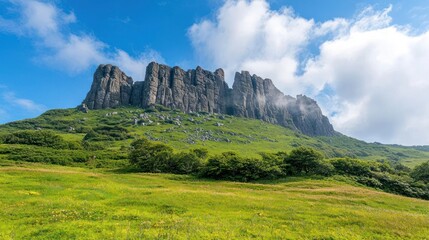 Obraz premium Rocky Mountain Peak With Lush Green Meadow Under Blue Sky