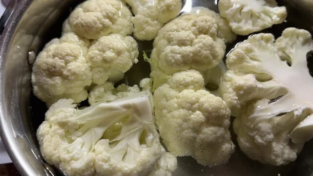 Cauliflower pieces in hot water during their blanching in pot