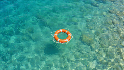 Naklejka premium Red and White Lifebuoy Floating on Calm Blue Sea Water