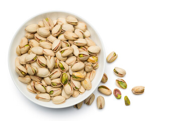 Pistachio nuts into bowl on white background. Top view.