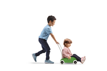 Boy pushing a little girl in a wooden toy cart