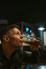 A man casually sips his drink, fully embracing the relaxed atmosphere while savoring a delightful...