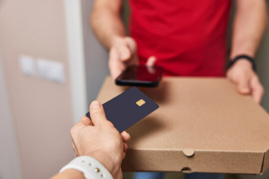 Woman using black credit card for payment of Pizza delivery man, close-up - Powered by Adobe