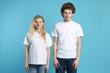 Fototapeta premium Young woman and man wearing blank white t-shirts on light blue background. Mockup for design