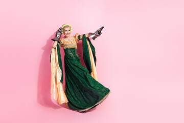 Fototapeta premium Elegant medieval woman in royal attire with modern accessories against a pink background