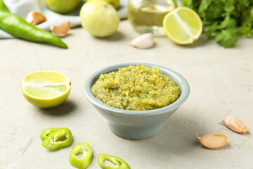 Delicious salsa sauce in bowl and products on light textured table, closeup