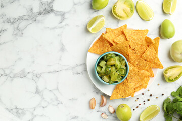 Delicious salsa with nachos on white marble table, flat lay. Space for text