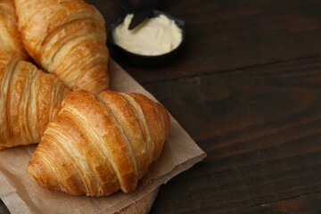Tasty fresh croissants served with butter on wooden table, closeup. Space for text