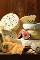 Different types of cheese, figs and rosemary on table, closeup