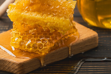 Golden honey with honeycomb on wooden cutting board. Organic food or alternative medicine concept.