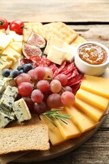 Different types of delicious cheese and other snacks on wooden table, closeup