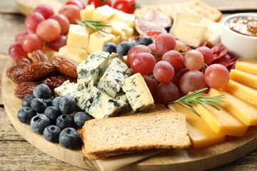 Different types of delicious cheese and other snacks on wooden table, closeup