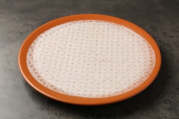 Edible rice paper sheets on grey textured table, closeup
