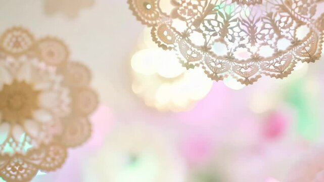 Smooth tilt upward video of delicate, white doilies gently floating through a blurred background of soft pastel colors, radiating a vintage and elegant atmosphere