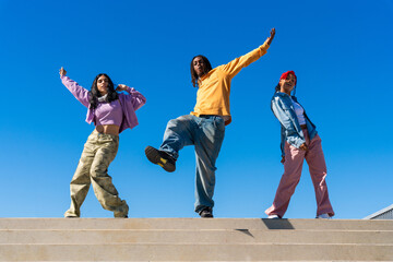Multiethnic group of young hip hop dancers wearing colorful streetwear dancing outdoors - Stylish multiracial rap crew members meeting and having fun together