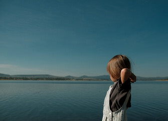 Fototapeta premium kid throwing rock into lake on sunny day