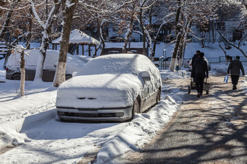 Car is covered in snow and is parked on the side of the road