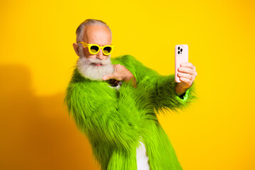 Charismatic senior man in lime green fur showcasing energetic personality in eccentric fashion on yellow background